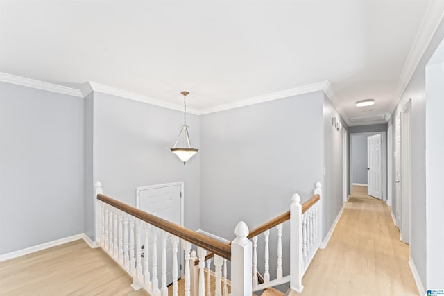 corridor with crown molding, baseboards, an upstairs landing, and light wood-style flooring