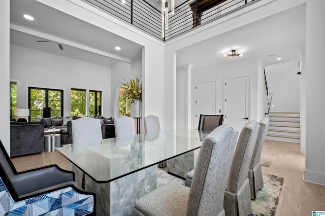 dining room featuring wood finished floors, stairway, a high ceiling, and recessed lighting