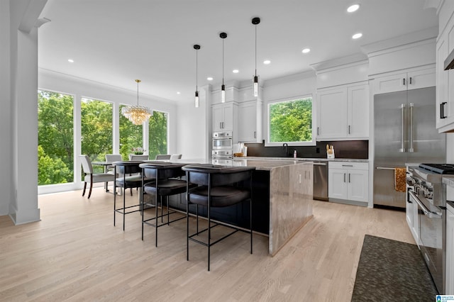 kitchen with high end appliances, a kitchen island, light wood-type flooring, recessed lighting, and white cabinetry