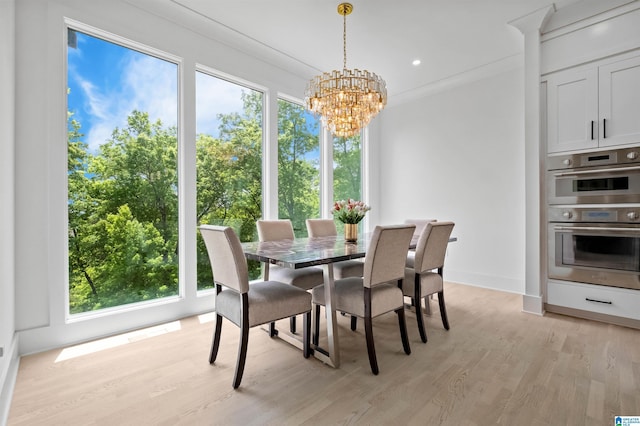 dining room featuring plenty of natural light, a chandelier, light wood-style floors, baseboards, and ornamental molding