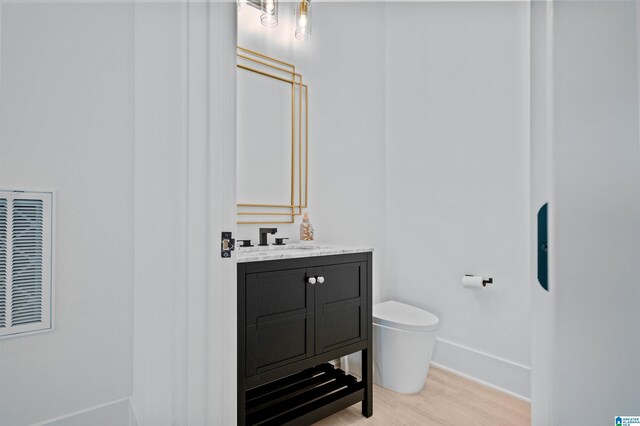 bathroom with wood finished floors, toilet, baseboards, and vanity