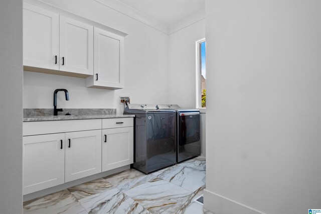 clothes washing area with washer and clothes dryer, light marble finish flooring, and cabinet space