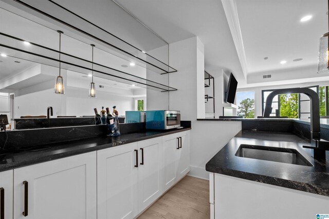 bar featuring stainless steel microwave, a sink, recessed lighting, light wood-style flooring, and pendant lighting