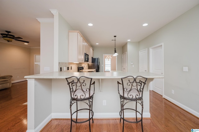 124 Blackstone Ct, Chelsea, AL 35043 - kitchen with light wood-type flooring, light countertops, a peninsula, and black appliances