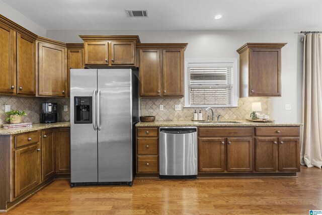 kitchen with visible vents, light stone countertops, tasteful backsplash, a sink, and appliances with stainless steel finishes