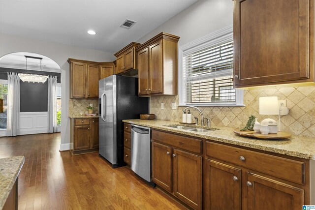 kitchen with visible vents, dark wood-style flooring, arched walkways, a sink, and stainless steel appliances