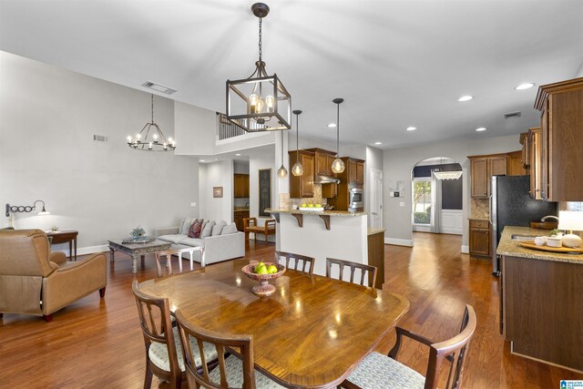 dining room with visible vents, arched walkways, a chandelier, and dark wood-style floors