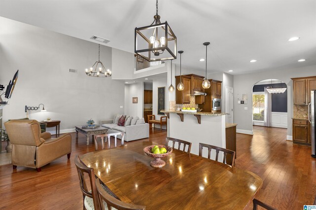 dining area featuring arched walkways, a chandelier, dark wood-style floors, and visible vents