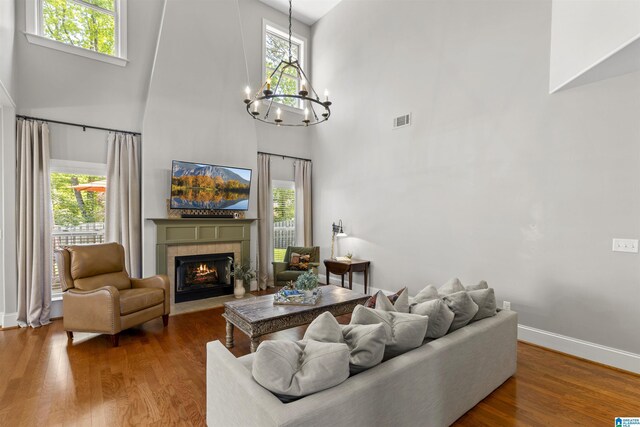 living room with plenty of natural light, visible vents, a notable chandelier, and a towering ceiling