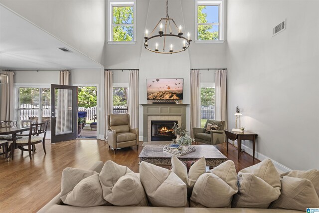 living room featuring a high ceiling, an inviting chandelier, visible vents, and a fireplace