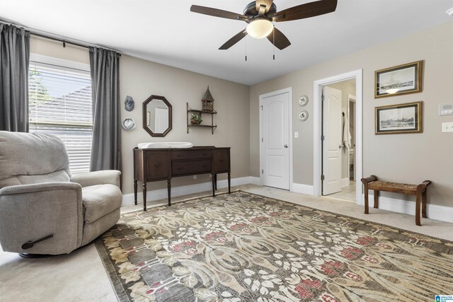 living area featuring baseboards, ceiling fan, and light carpet