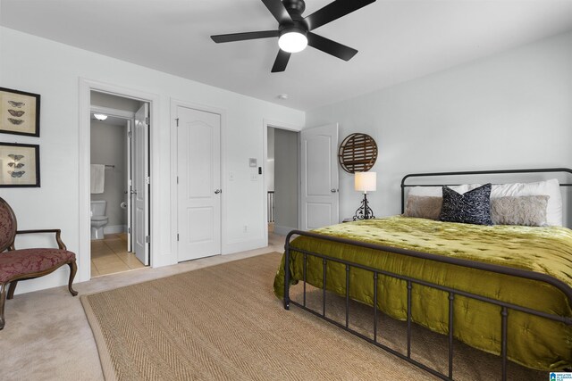 bedroom featuring baseboards, ensuite bathroom, and light colored carpet