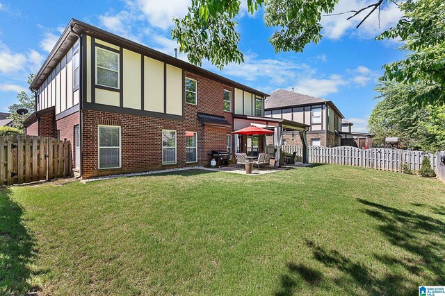 rear view of property with a fenced backyard, brick siding, board and batten siding, a patio area, and a lawn