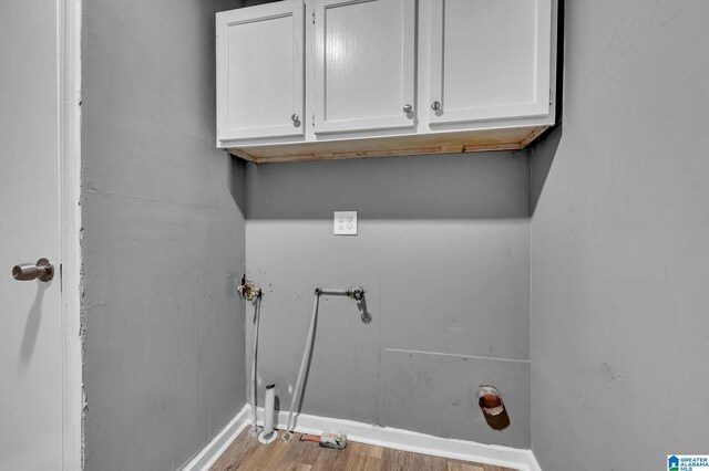 washroom with light wood-style floors, baseboards, washer hookup, and cabinet space