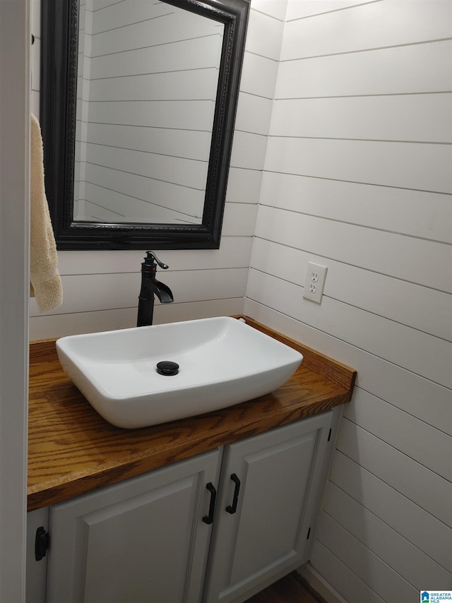 bathroom with vanity and wood walls