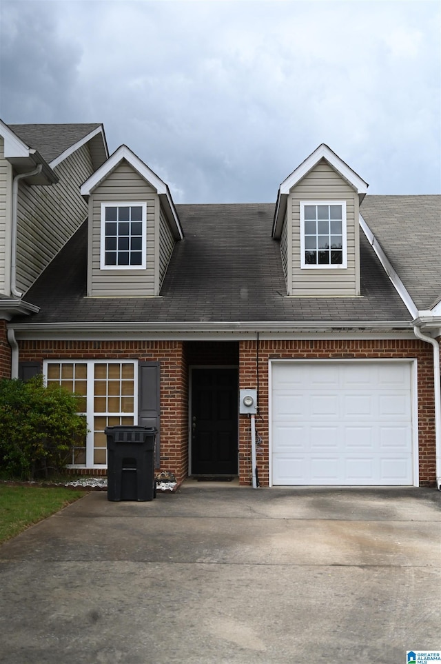 view of property with roof with shingles, an attached garage, concrete driveway, and brick siding