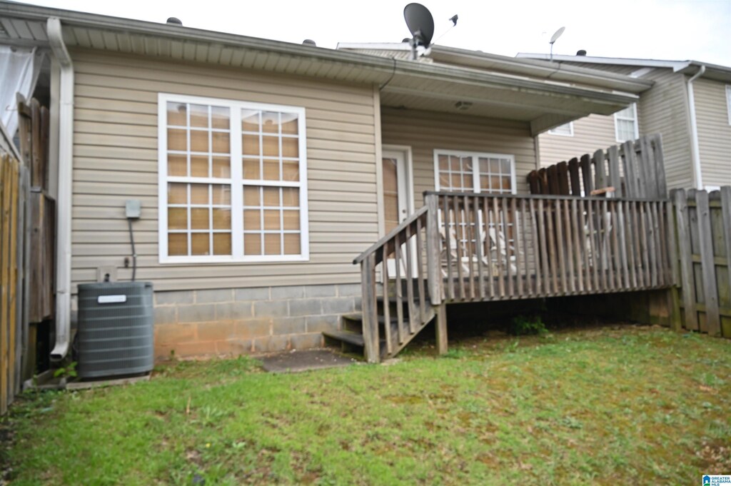 back of house featuring a lawn, central AC unit, fence, and a deck
