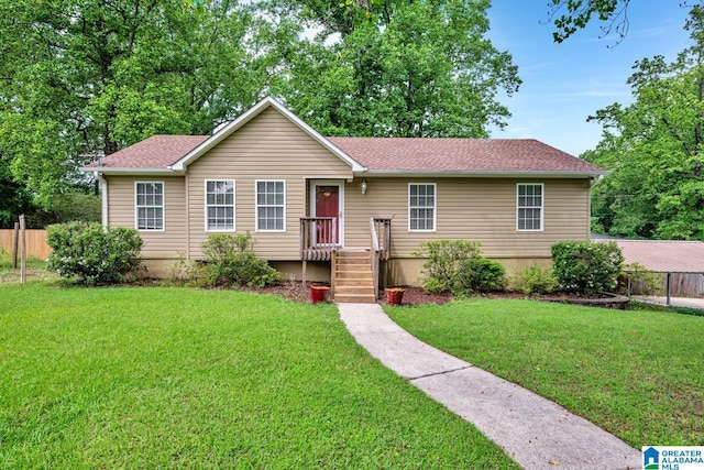 ranch-style home with fence, a shingled roof, and a front lawn