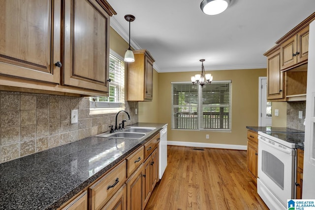 kitchen with dark countertops, a sink, a notable chandelier, light wood-style floors, and white appliances