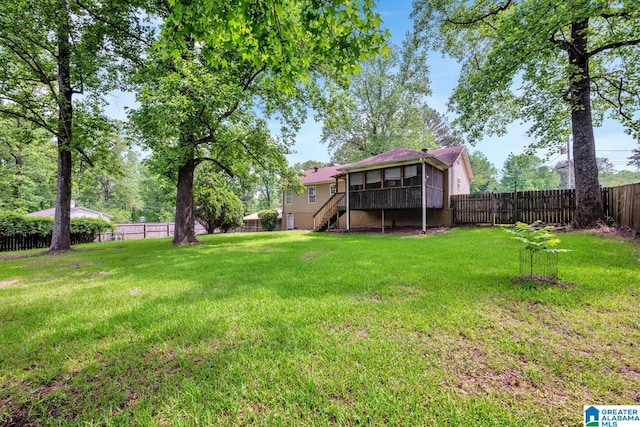 view of yard with a fenced backyard, a sunroom, and stairs