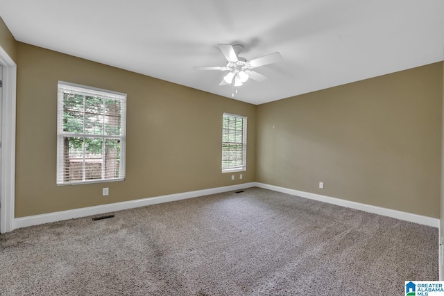 carpeted spare room with ceiling fan, visible vents, and baseboards