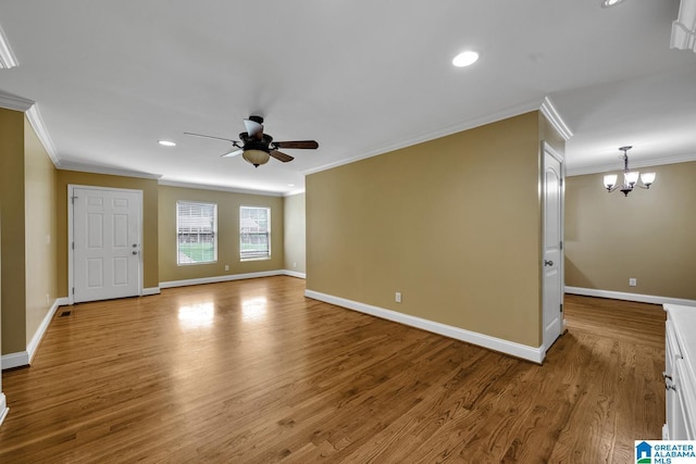 unfurnished living room with baseboards, ornamental molding, wood finished floors, and ceiling fan with notable chandelier