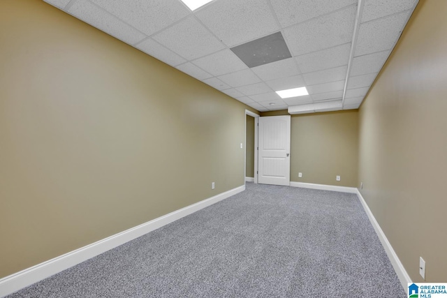 carpeted empty room with baseboards and a drop ceiling