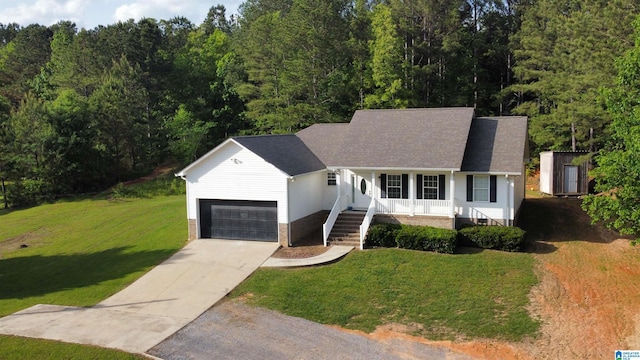 ranch-style home featuring a front lawn, an attached garage, a porch, driveway, and a forest view