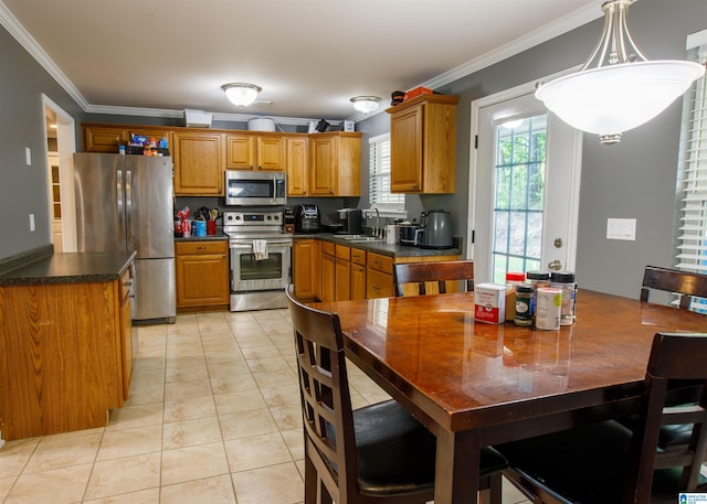 kitchen with brown cabinets, dark countertops, appliances with stainless steel finishes, a sink, and ornamental molding