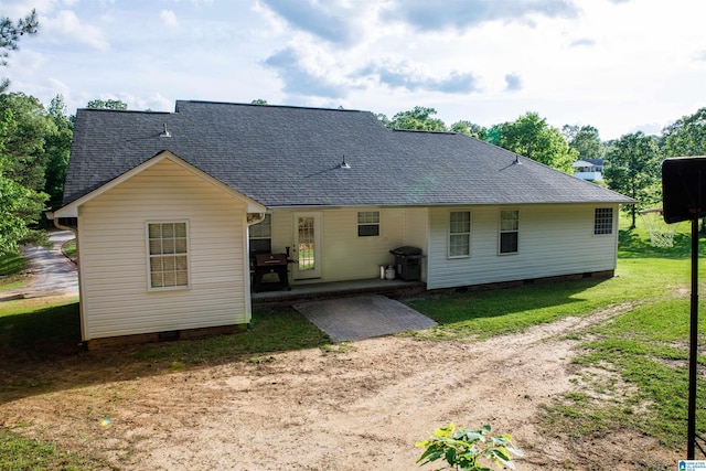 rear view of property with a lawn, a shingled roof, a patio area, and crawl space