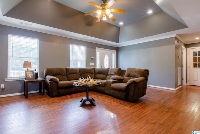 living room with visible vents, ornamental molding, baseboards, ceiling fan, and a tray ceiling