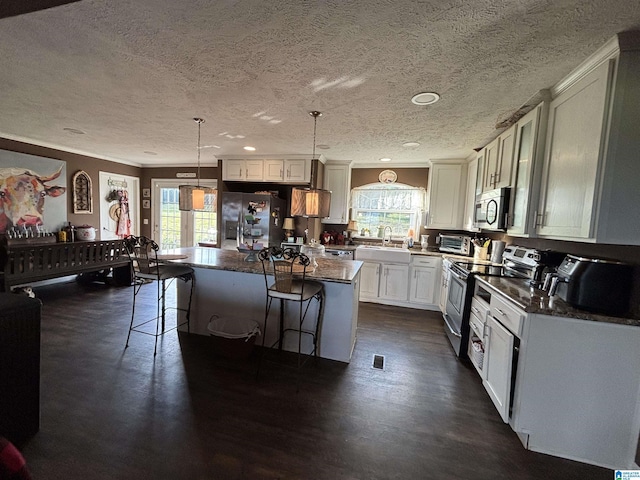 1525 Marvin Adcock Rd, Hayden, AL 35079 - kitchen featuring appliances with stainless steel finishes, a textured ceiling, plenty of natural light, ornamental molding, and a kitchen breakfast bar