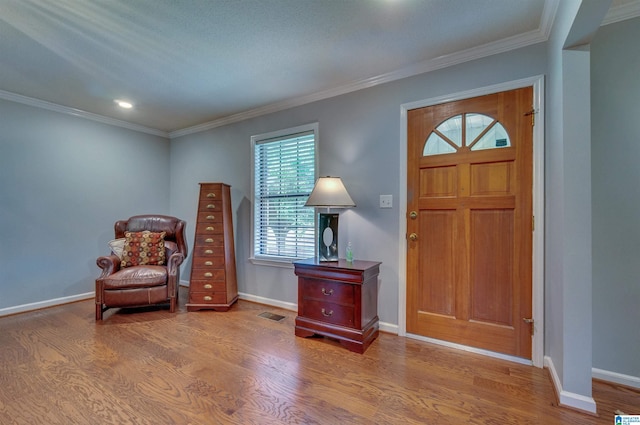 foyer with visible vents, ornamental molding, baseboards, and wood finished floors