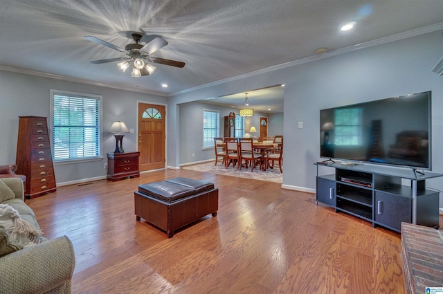 living room with plenty of natural light, ornamental molding, and wood finished floors