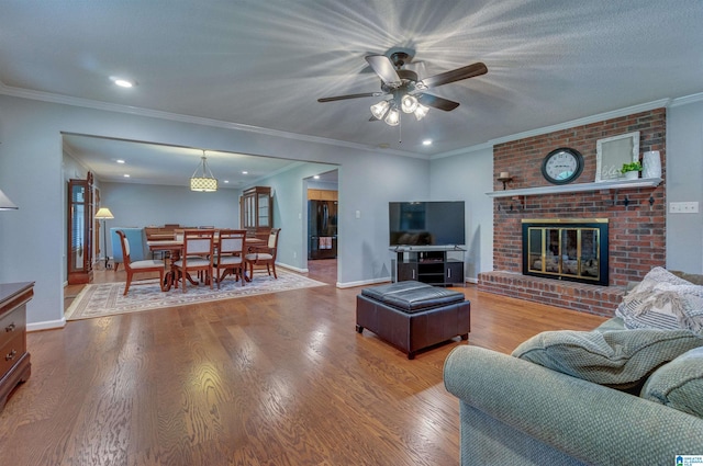 living room with a ceiling fan, a fireplace, wood finished floors, baseboards, and recessed lighting