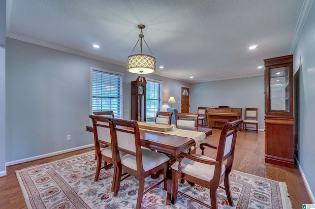 dining space featuring ornamental molding, a textured ceiling, and wood finished floors