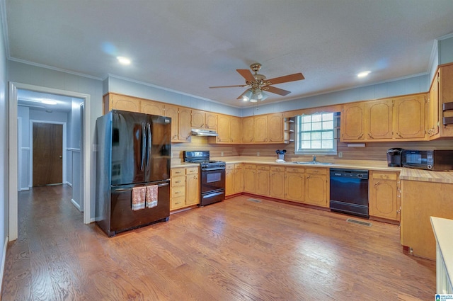 kitchen featuring ornamental molding, light wood-style floors, light countertops, under cabinet range hood, and black appliances