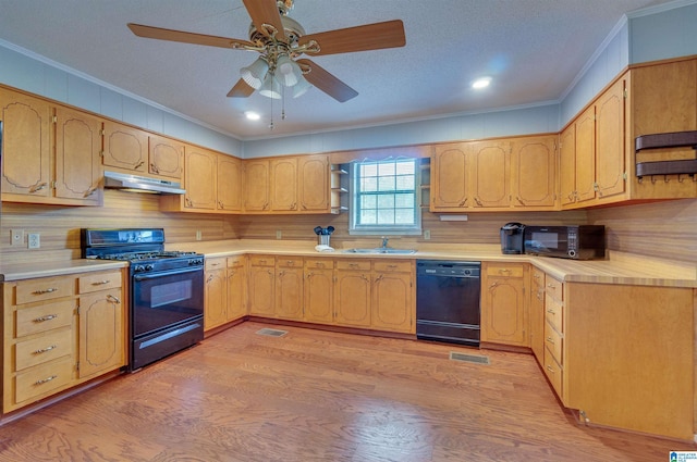 kitchen featuring a sink, light wood finished floors, under cabinet range hood, ornamental molding, and black appliances