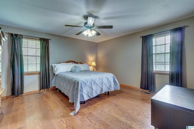 bedroom featuring light wood-style floors, baseboards, ceiling fan, and visible vents