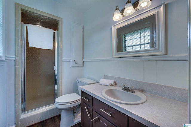 bathroom with vanity, a stall shower, toilet, and wood finished floors
