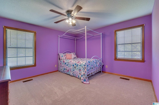 carpeted bedroom with a textured ceiling, ceiling fan, visible vents, and baseboards