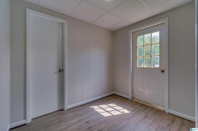 unfurnished room with baseboards, a drop ceiling, and wood finished floors