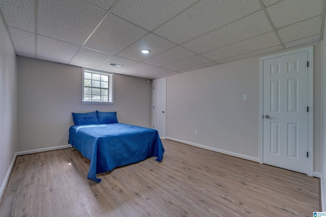 bedroom with visible vents, a paneled ceiling, baseboards, and wood finished floors