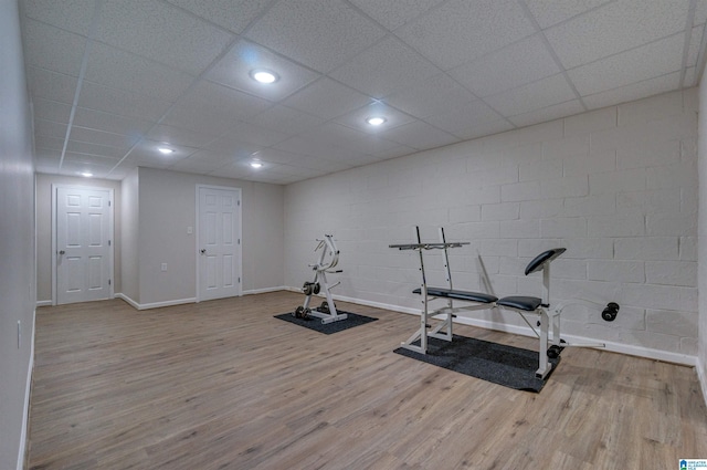 exercise room with baseboards, wood finished floors, and concrete block wall
