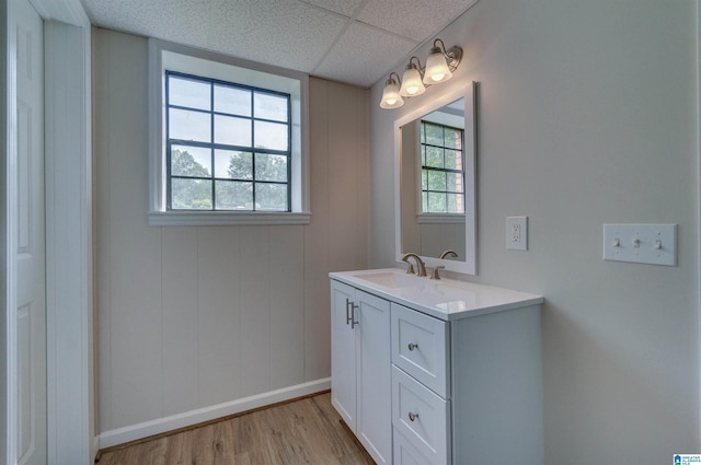 bathroom featuring vanity, baseboards, a drop ceiling, and wood finished floors