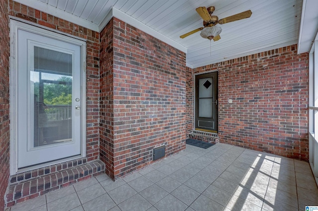 view of exterior entry featuring brick siding and ceiling fan