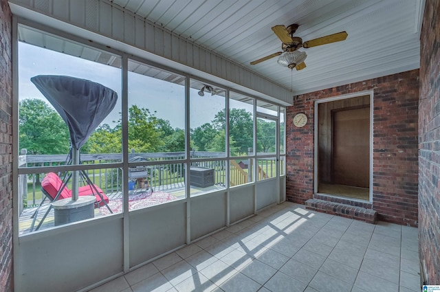 unfurnished sunroom with a ceiling fan and a wealth of natural light