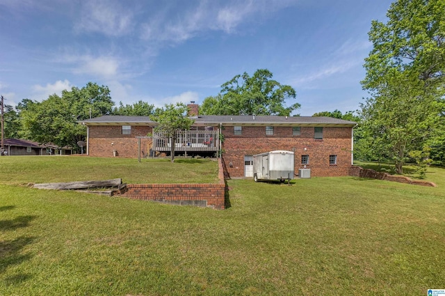 rear view of house with a yard, brick siding, a wooden deck, and a chimney