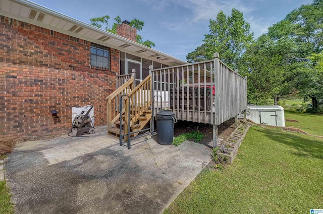exterior space featuring brick siding, a deck, a chimney, a patio area, and a lawn