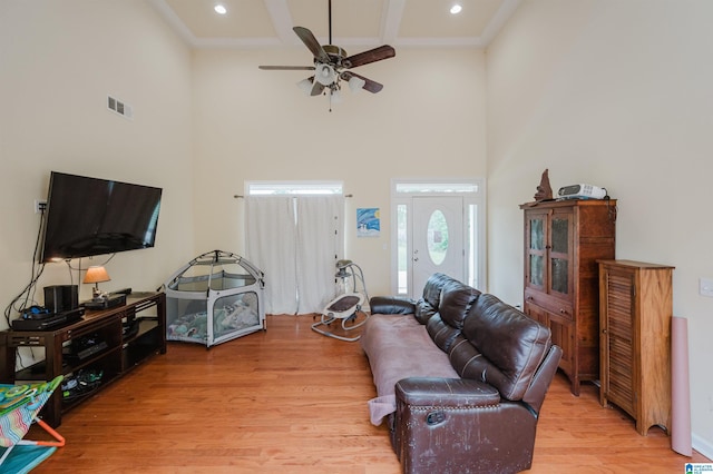 living room featuring a ceiling fan, a towering ceiling, visible vents, light wood-type flooring, and beamed ceiling